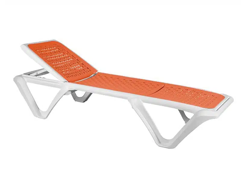 La imagen muestra una tumbona reclinable de color blanco y naranja. La estructura de la tumbona es de plástico blanco, con un diseño moderno y ergonómico. La superficie para acostarse es de color naranja y tiene un patrón perforado para mayor comodidad y ventilación. La tumbona tiene una parte ajustable en el respaldo para permitir diferentes posiciones de reclinado