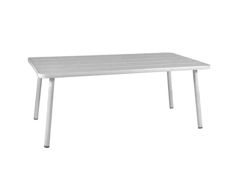 La imagen muestra una mesa rectangular de color blanco. La mesa tiene un diseño moderno y minimalista con una superficie lisa y ligeramente texturizada. Está sostenida por cuatro patas delgadas y rectas, también de color blanco