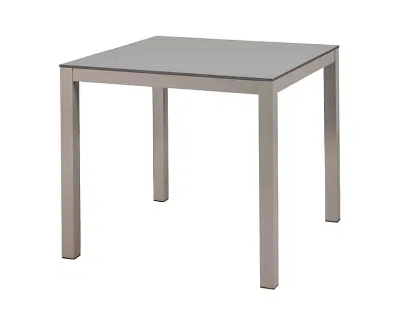 La imagen muestra una mesa cuadrada de diseño simple y moderno, con una superficie blanca con tablero HPL y cuatro patas hechas de aluminio . El estilo es minimalista y elegante