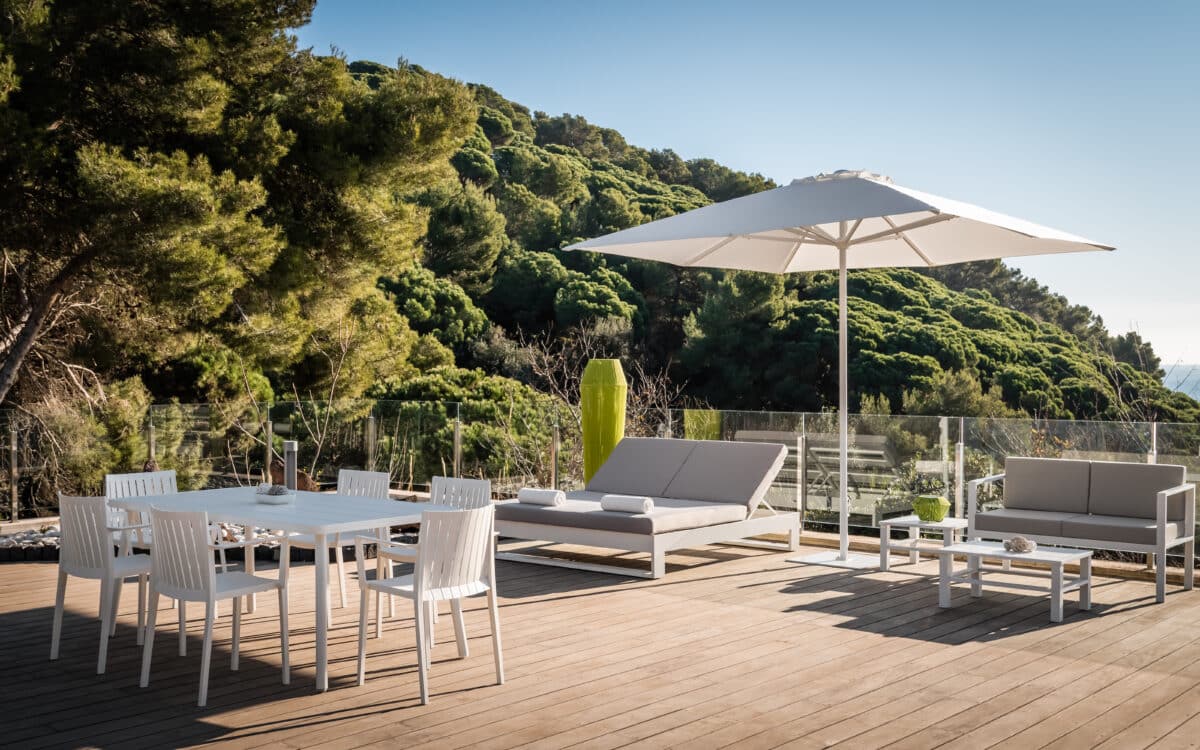 conjunto de sofa sillas mesas y un parasol con una montaña de fondo